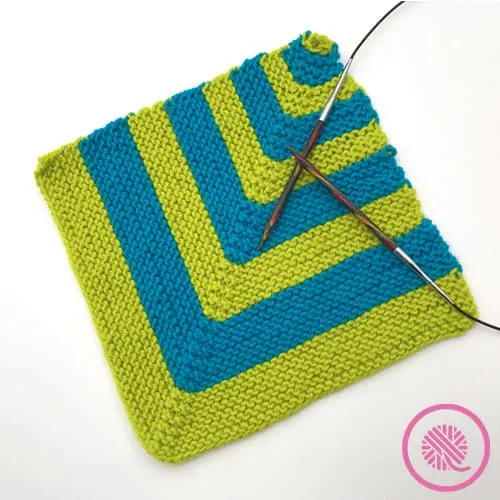 green and blue mitered square with knitting needles